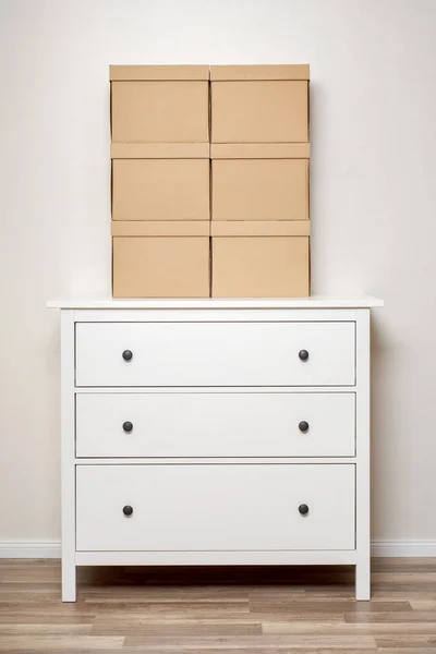 Kartonové krabice na bílé dřevěné komody — Stock fotografie