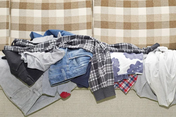 Морщинистая одежда лежит на диване — стоковое фото