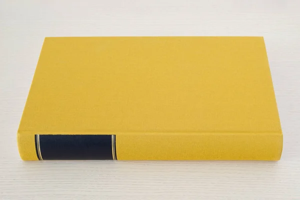 Yellow book with black frame on spine on the table — Stock Photo, Image