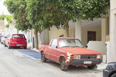 Eski paslı kırmızı araba sokakta park edilmiş.