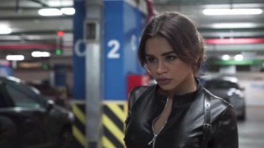 çekici kız siyah deri kostüm / siyah deri kostümlü çekici kız Park arabalar arasında yürür