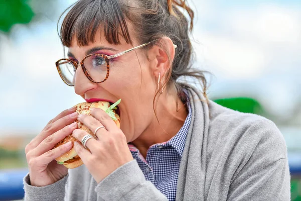 Uma mulher a comer um hambúrguer — Fotografia de Stock