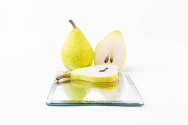 Lezzetli bir armut yanında cam bir tabakta yeşil armut dilimleri beyaz bir zemin üzerinde izole edilmiş taze hasat edilmiş tatlı armutlar