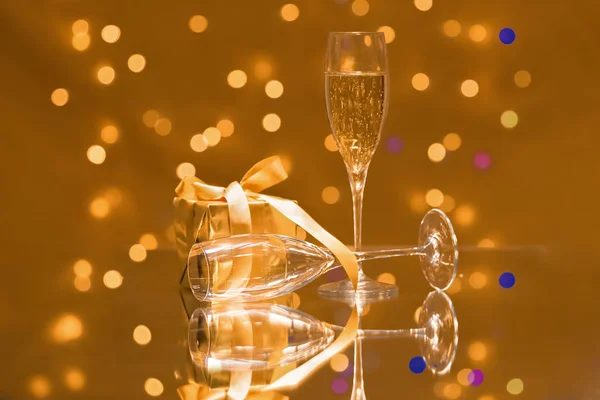 Copos de champanhe com uma caixa de presente dourada — Fotografia de Stock