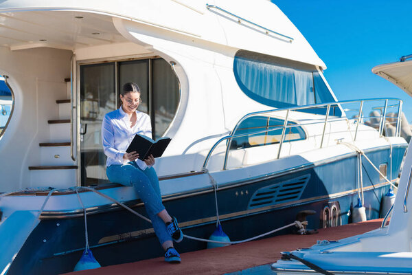 Woman reads a book sitting on a boat