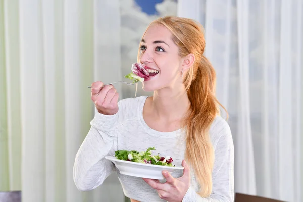 Mulher sorri enquanto come uma salada saudável — Fotografia de Stock