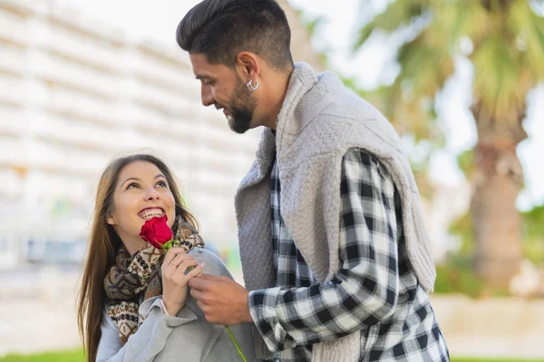 一位年轻女子收到了一位年轻男子送的红玫瑰 — 图库照片