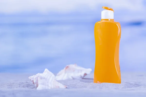 Orange tabir surya botol dengan sepasang kerang laut — Stok Foto