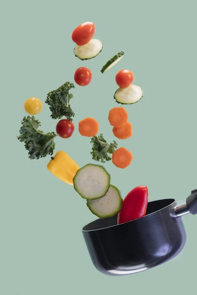 Saucepan with assorted vegetables flying in the air