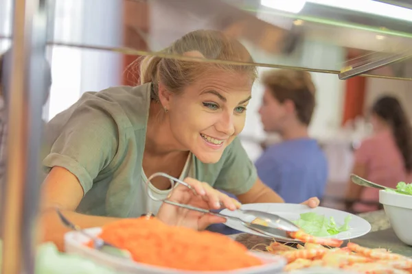 Woman serving herself at a cafeteria — Stock Photo, Image