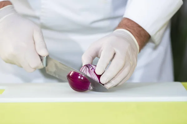 Chef cuts a fresh red onion in half — Stock Photo, Image