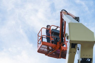 İşçi telefonunu yüksek bir platformda kullanıyor.