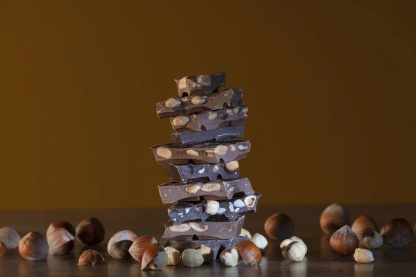 Pile de morceaux de chocolat entourés de noisettes — Photo