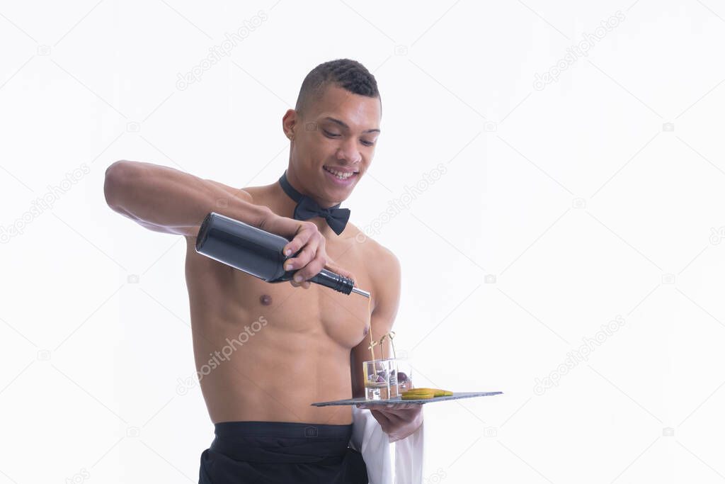 Shirtless young waiter filling glass shots with liquor