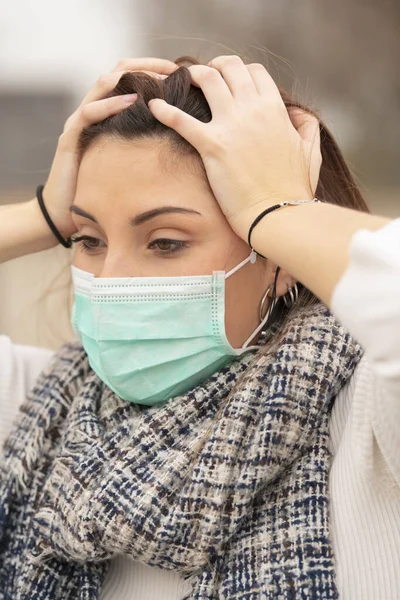 Teenager wearing a mask clutching her head — Stok fotoğraf