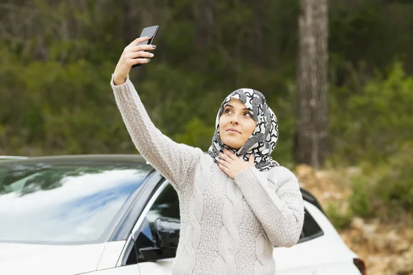 Mulher usando um lenço de cabeça leva uma selfie — Fotografia de Stock