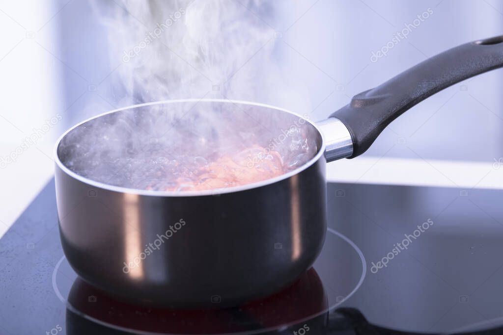 Saucepan with boiling water on a glass ceramic cooktop