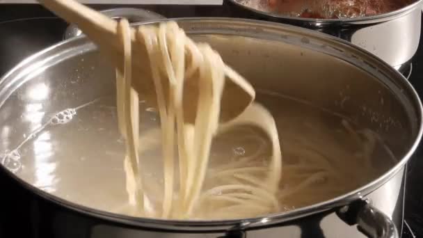 Kook spaghetti en roer met een houten lepel in kokend water in een metalen pan. concept van deegwaren — Stockvideo