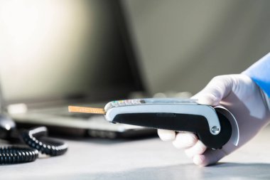 Kredi kartı okuyucusunun elinde eldiven tutan bir kart var.