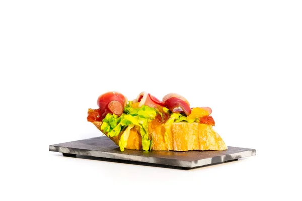 关闭了一个美味的开放三明治与脆面包和各种肉类和蔬菜在黑暗的盘子在一个轻背景 西班牙美食概念 — 图库照片