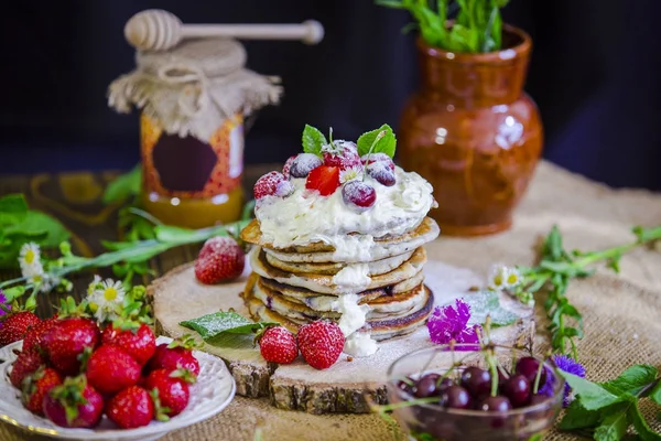 Delicious pancakes with berries on the authentic wooden stand. Summer food, pancakes sprinkled with cream and berries