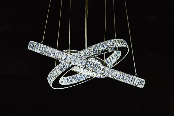 fashionable designer chandelier in the form of rings decorated with glass crystals diamonds, chandelier isolate on black background