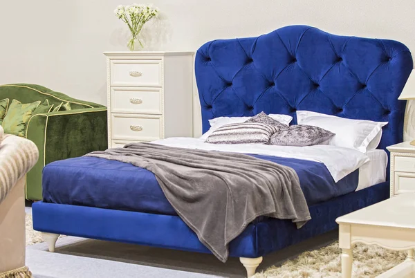 Роскошная спальня в античном стиле с синей бархатной кроватью и белой тумбочкой — стоковое фото