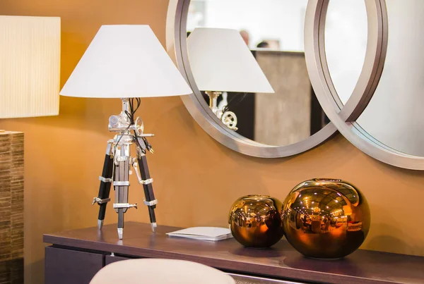 Diseño moderno de la habitación. Hest de cajones con una lámpara de mesa en un trípode, jarrones decorativos redondos de cobre . — Foto de Stock