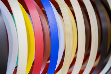 Solid color or wood grain PVC edge banding tape. ABS edge banding. Set of colored thermoplastic edges. Multicolored bobbins of PVC edge and melanin for the manufacture of furniture clipart