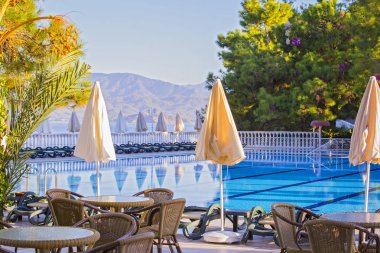 Yüksek katlı konforlu. Boş hotel, Yüzme Havuzu, deniz, palmiye ağaçları, şemsiye, tablolar, güneşlenme yatakları, arka planda dağlar