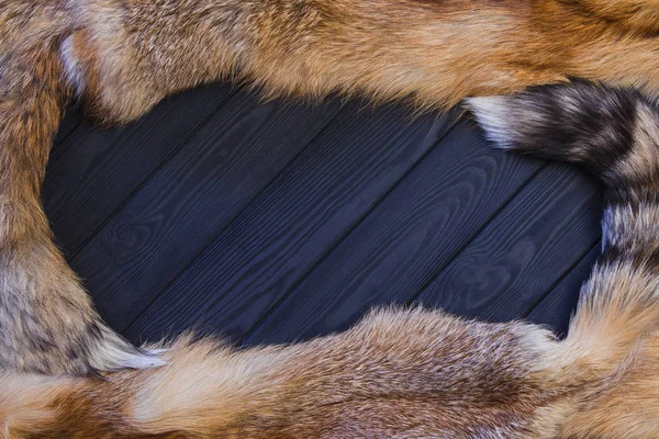 Pelle di volpe rossa su uno sfondo di legno nero. Bella pelliccia di una volpe rossa con code — Foto Stock