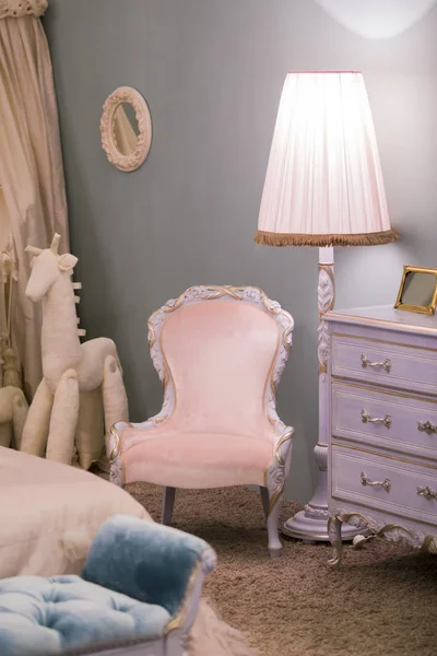 Розовая маленькая комната принцессы с напольной лампой рядом с детской игрушечной лошадью и красивой комодом, рамками на стенах. Шикарный интерьер спальни — стоковое фото