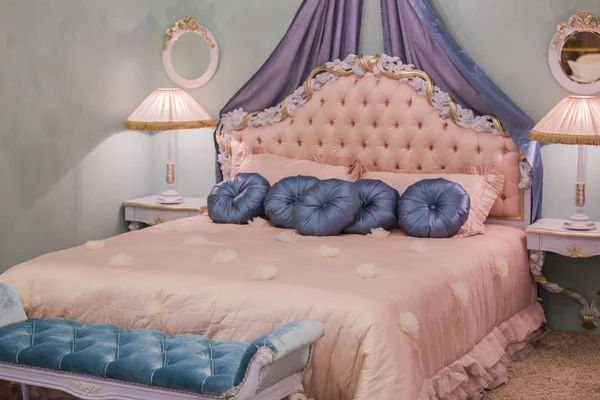 Розовая маленькая комната принцессы с атласными подушками, прикроватными лампами, тумбочками, рамками на стенах. Шикарный интерьер спальни — стоковое фото