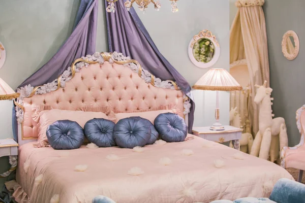 Розовая маленькая комната принцессы с атласными подушками, прикроватными лампами, тумбочками, рамками на стенах. Шикарный интерьер спальни — стоковое фото