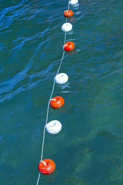 Rope with buoys above the surface of the blue water.  Bounding buoys at sea — Stock Photo, Image