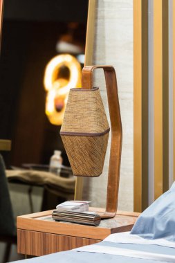 Ahşap bir komodinin üzerinde kumaş ve deri bir tonu olan bir yatak başı lambası. Modern iç tasarım.