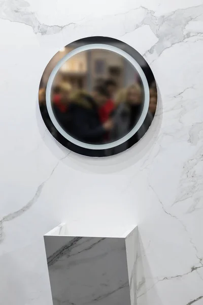 Marble sink on the background of a marble wall, white bathroom completely in marble with round mirror.