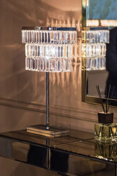 Classic crystal reading lamp on bedside table in cozy gold bedroom interior.