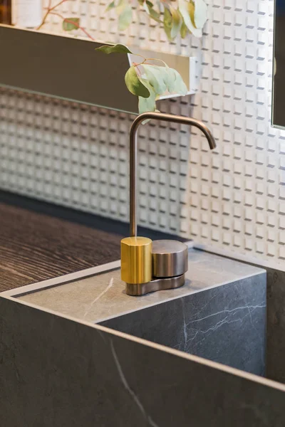 Bathroom interior grey marble sink and golden tap. Beautiful modern bathroom design.