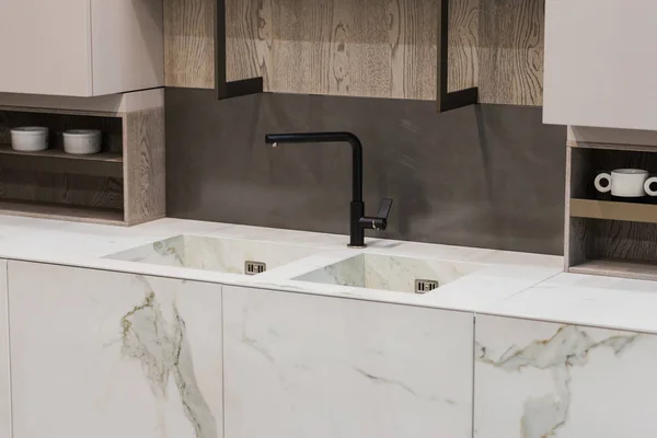 Modern mutfak beyaz mermer desen, siyah musluk ve mermer lavabo, asılı ahşap büfe rafları.