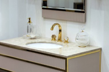 Altın musluğu ve tesisatı olan güzel bir lavabo. Mermer lavabo, yuvarlak ayna, altın şeker kutusu..