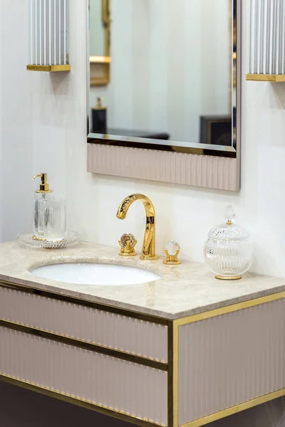 Altın musluğu ve tesisatı olan güzel bir lavabo. Mermer lavabo, yuvarlak ayna, altın şeker kutusu..