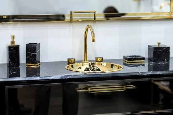 Altın musluğu ve tesisatı olan güzel siyah mermer bir lavabo. Altın lavabo, kurşun ayna, mermer siyah şeker kutuları..
