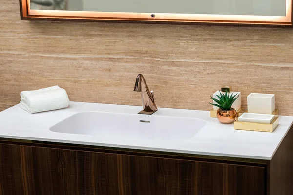 A beautiful washbasin with a copper tap and fittings. Marble sink, square led mirror, wooden cabinet.