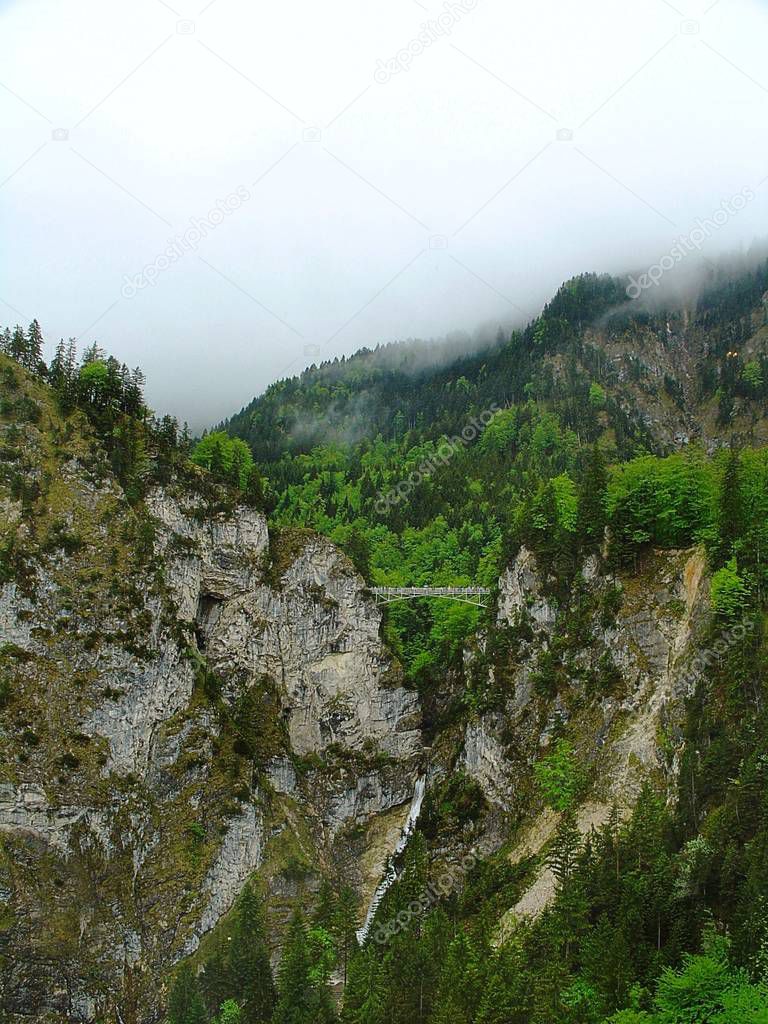 Beautiful view of bridge in mountains. Green trees and white clouds background. Austria. Alps mountains.Beautiful nature background.