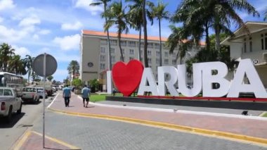 Büyük beyaz büyük harfler Merkezi Oranjestad, Aruba başkenti bir Road Aruba seviyorum. Büyük kırmızı kalp kelime aşk yerine. Mavi gökyüzü ve bulutlar beyaz arka plan.