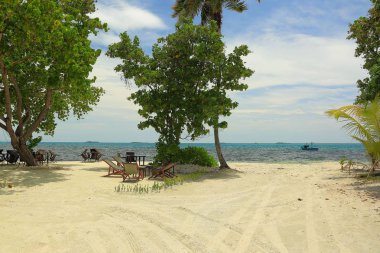 Okyanus kıyısında açık restoran muhteşem manzarası. Yeşil ağaçlar, mavi gökyüzü ve bulutlar beyaz arka plan üzerinde beyaz kum ve turkuaz su. Hint Okyanusu. Maldivler.
