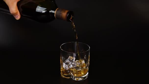 短片中 威士忌倒入玻璃杯中 背景是黑色的冰块 慢动作 漂亮的背景 — 图库视频影像