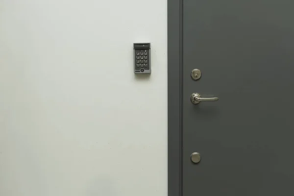 Close up view of grey metal door with digital code lock to the left. Security concept,
