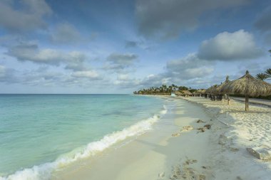 Beyaz kumsal ve turkuaz dalgalar. Turkuaz deniz suyu ve mavi gökyüzü. Aruba Adası 'nın Kartal Sahili. Güzel arka planlar.